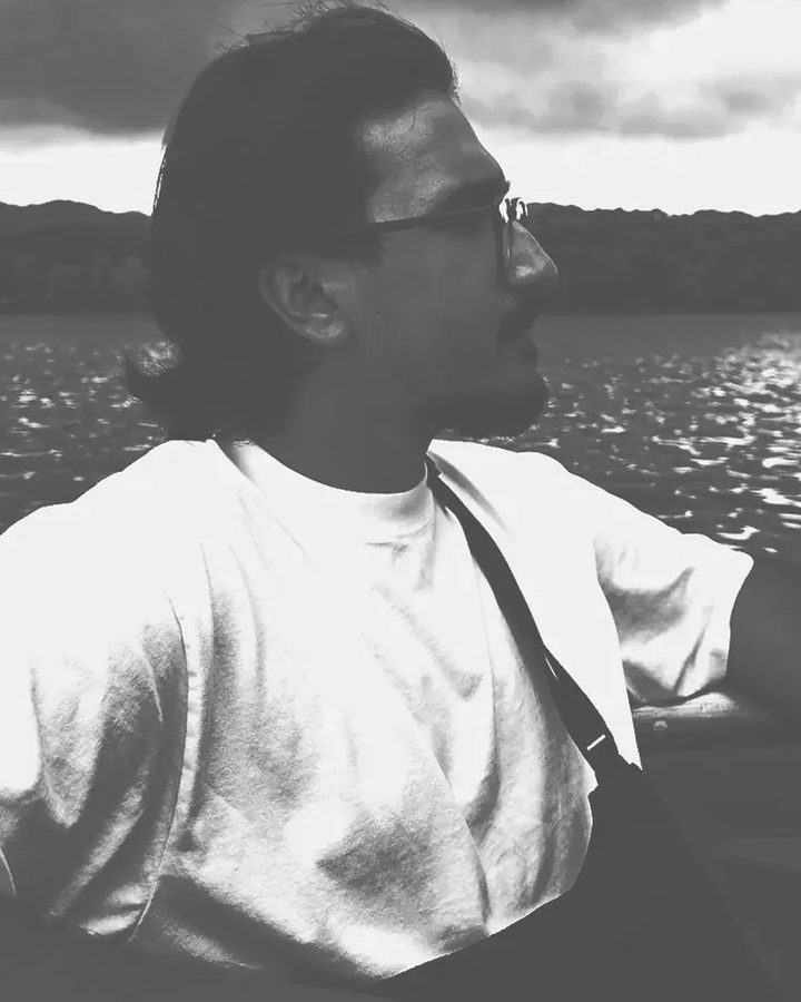Salman in profile on a boat, looking out over a lake.
