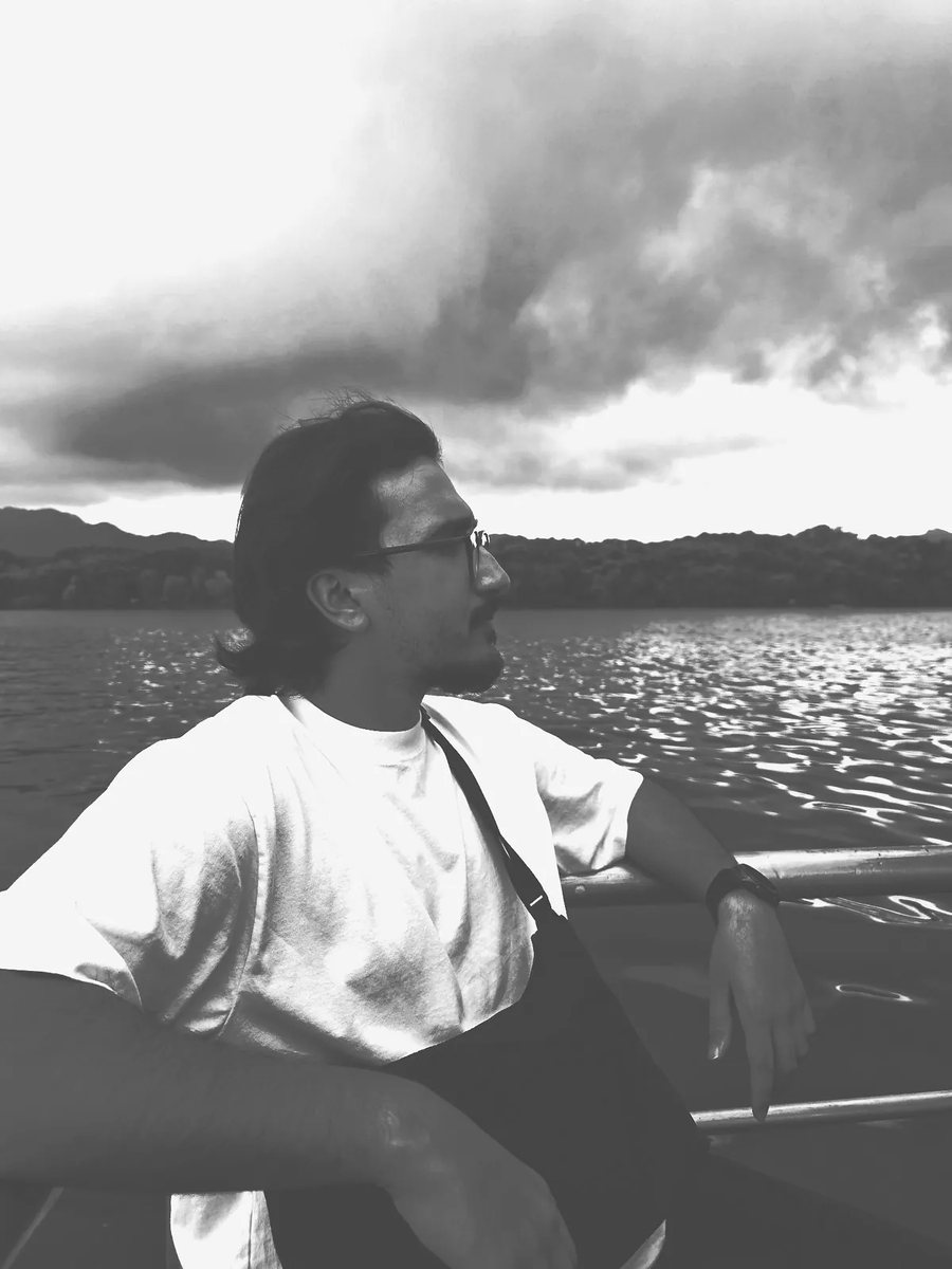 Salman on a boat, looking out across the water under a heavy sky.