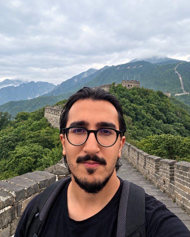 Salman on the Great Wall, the wall running off behind him into green hills.